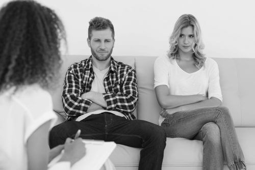 unhappy young couple sitting apart of sofa